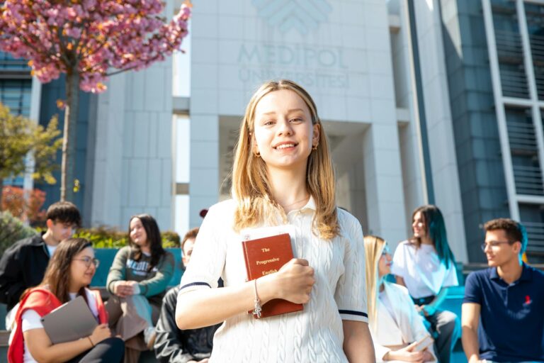 Happy university students socializing on campus, with a focus on a smiling young woman holding a book.
